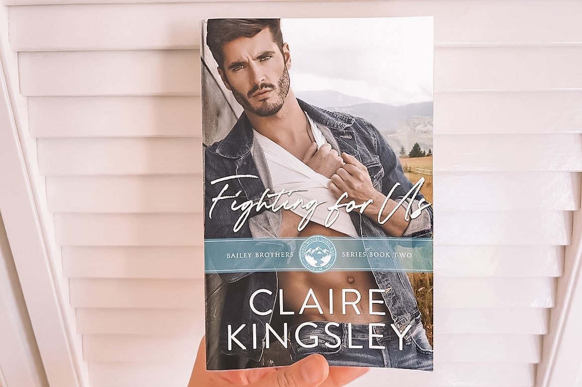 book pics – 19 paperback of fighting for us by Claire kingsley being held by female hand
